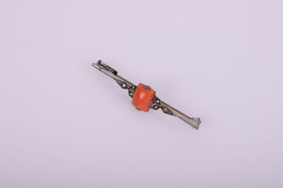 a close up of a small orange bead on a white surface