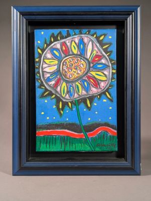 un tableau représentant une fleur, dans un cadre bleu, posé sur une table