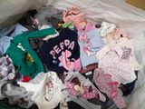 a bag full of baby clothes sitting on top of a bed