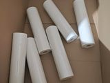 four rolls of white paper in a cardboard box