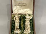 deux figurines dans une boîte posée sur une table recouverte d'une nappe blanche