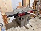 an image of a table saw sits in a room with a lot of wood