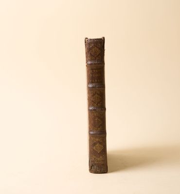 un vieux livre posé sur une table à côté d'un mur blanc