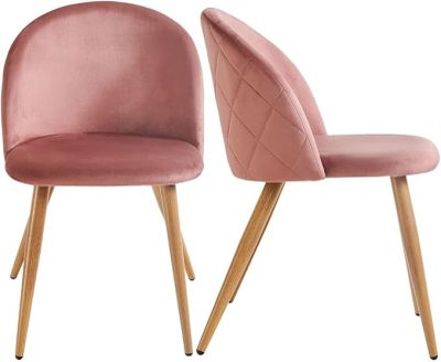 a pair of pink velvet chairs with wooden legs
