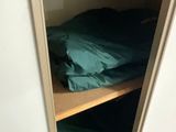 a closet with a bed and a shelf with clothes on it