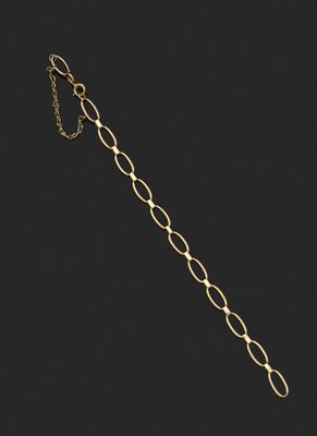 un gros plan d'un bracelet en or muni d'une chaîne, sur fond noir