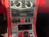 une photo du tableau de bord d'une voiture rouge avec un bouton de changement de vitesse rouge