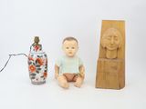 a small doll sitting next to a vase and a lamp
