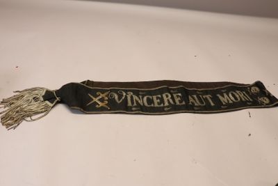 une vieille écharpe noire et dorée sur laquelle est inscrit « ginger at home »
