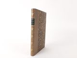 an old book sitting on top of a white table next to a white wall