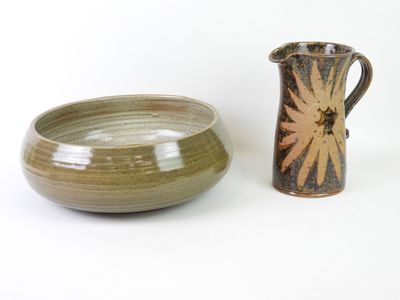 bowl and pitcher sitting next to each other on a white surface