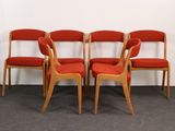 four red chairs are lined up against a white wall