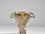 un vase en verre orné d'un visage, posé sur une table
