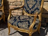 pair of gold and blue upholstered chairs in front of a stone wall