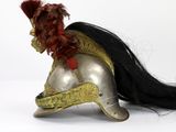 a silver helmet with a red feather on top of it