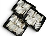three silver plated utensils in a black box on a white surface
