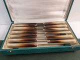 a green case with six knives inside of it