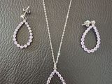 a necklace and earring set with pink crystals on a black leather surface