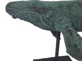 statue of a bronze whale on a black stand on a white background
