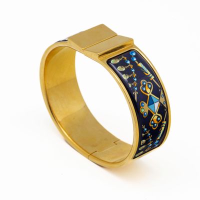 un gros plan sur un bracelet en or orné d'un motif bleu et jaune