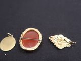 trois broches dorées et rouges sur un fond noir