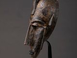 a close up of a wooden mask on a metal stand