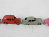 four toy cars are lined up in a row on a white surface