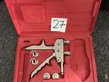 une boîte à outils rouge ouverte, contenant des outils, posée sur un tapis