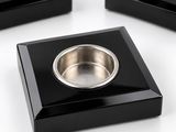 three black square shaped dishes with a metal bowl in the middle of them