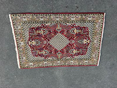 a red and white rug sitting on top of a cement floor
