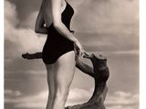 black and white photo of a woman in a bathing suit standing on a tree branch