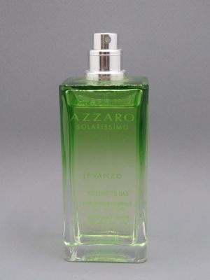 un gros plan d'un flacon de parfum posé sur une surface grise
