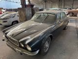 an old car parked in a garage with other cars in the background