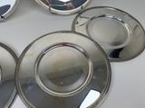 four silver plates with silver rims are sitting on a table