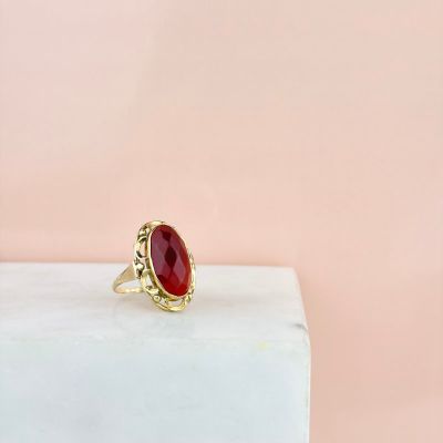 une bague en pierre rouge posée sur un bloc de marbre blanc