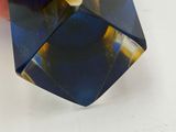 someone is holding a blue and yellow glass object in their hand