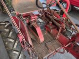 a red tractor parked in a garage next to a red car