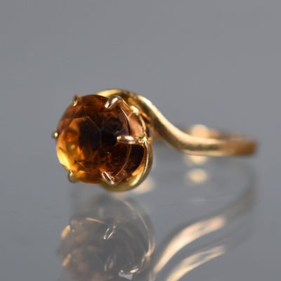 un gros plan d'une bague en or sertie d'une pierre brune