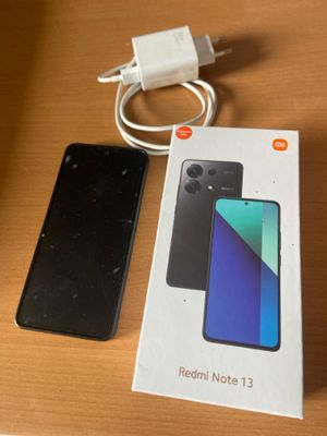 a box of redmi note 13 next to a charger on a table