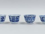four blue and white cups are lined up on a white surface