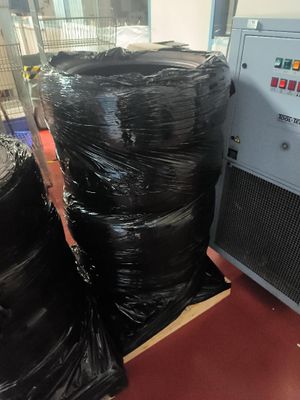 une pile de sacs en plastique noirs posée sur une palette à côté d'une machine