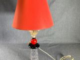 une image représentant une lampe avec un abat-jour rouge et un pied noir