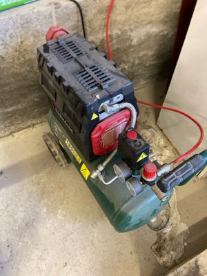 a small air compressor sitting on the floor next to a wall