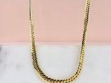 un collier à chaîne en or posé sur un comptoir en marbre