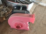 un souffleur rose posé par terre à côté d'un tas de vieilleries