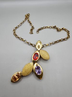 un gros plan d'un collier posé sur une surface blanche, avec une chaîne en or