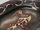 a plate with a bird painted on it sitting on a table