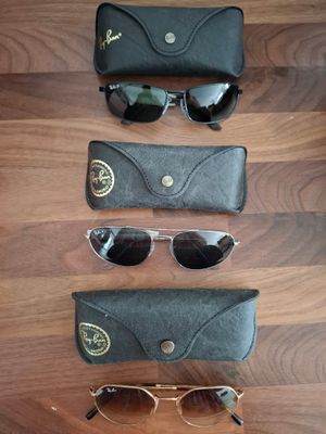 trois paires de lunettes de soleil sont alignées sur un parquet