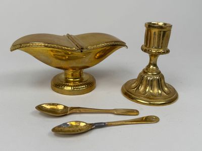a gold plate with spoons and a candle on it