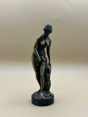 statue en bronze représentant une femme avec un chien, posée sur un socle blanc